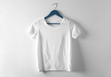 Hanger with white t-shirt on light background. Mockup for designの写真素材