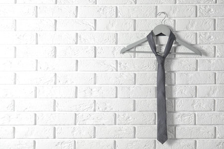Tie on wooden hanger against brick wall. Space for textの写真素材
