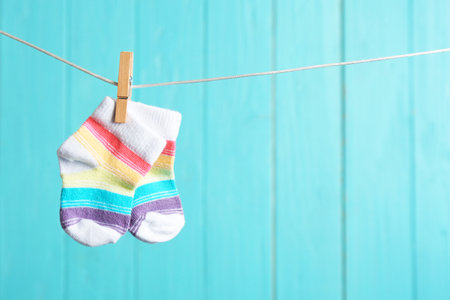 Baby socks on laundry line against color wooden background, space for text. child accessoriesの写真素材