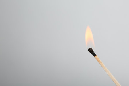 Burning match on gray background, space for textの写真素材