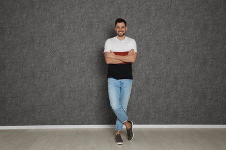 Full length portrait of handsome man against gray wall