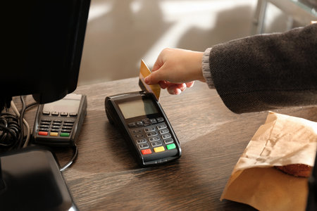 Woman with credit card using payment terminal at shop, closeupの写真素材