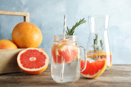 Composition with mason jar of infused water and grapefruits on tableの写真素材