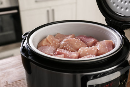 Fresh cut chicken in modern multi cooker on table, closeupの写真素材