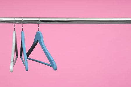 Empty clothes hangers on metal rail against color background. Space for textの写真素材