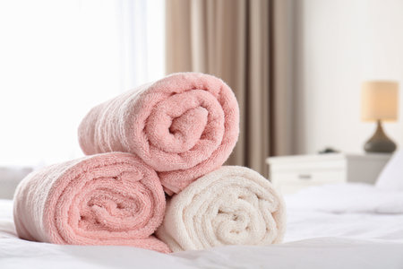 Rolled soft towels on bed in room. Space for textの写真素材