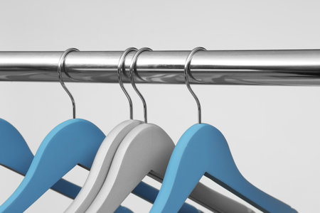 Empty clothes hangers on metal rail against light background, closeupの写真素材