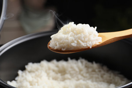 Spoon with tasty hot rice over cooker, closeupの写真素材
