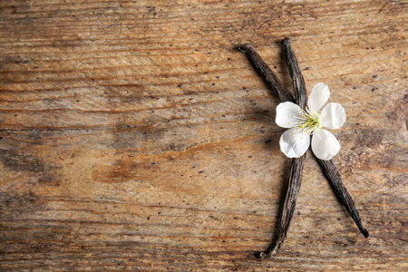 Flat lay composition with aromatic vanilla sticks and flower on wooden background. Space for textの写真素材