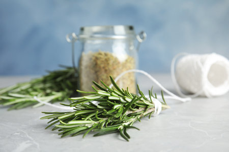 Jar with dried rosemary, twine and fresh twigs on tableの写真素材