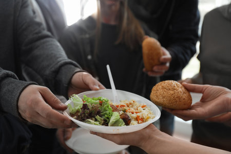 Poor man receiving food from indoor volunteers, closeup