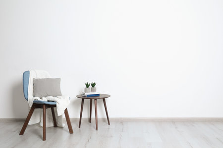 Stylish room interior with chair, pillow and plaid near white wall. Space for textの写真素材
