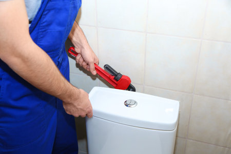 Male plumber repairing toilet tank in bathroom, closeupの写真素材