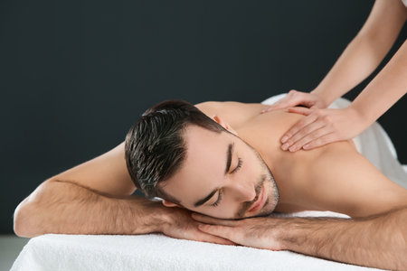 Handsome man receiving back massage on black background. Spa serviceの写真素材