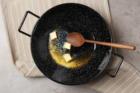 Frying pan with melting butter and spoon on gray table, top viewの写真素材