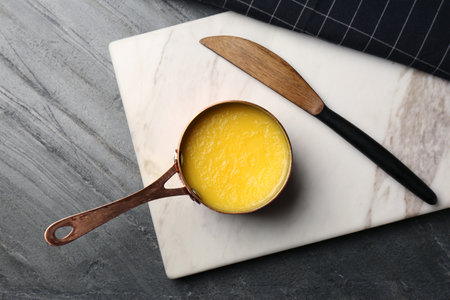 Stone board with saucepan of clarified butter and knife on table, flat layの写真素材