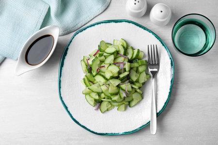 Plate of vegetarian salad with cucumber and onion served on table, flat layの写真素材