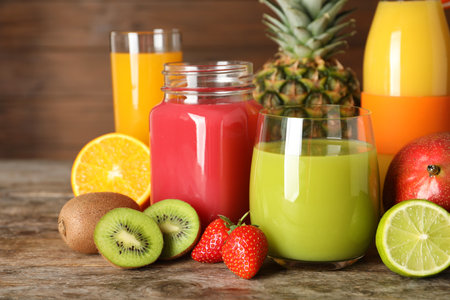 Glassware with different juices and fresh fruits on wooden backgroundの写真素材