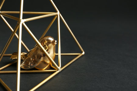 Decorative bird in gold pyramid on black background, closeup. Space for textの写真素材
