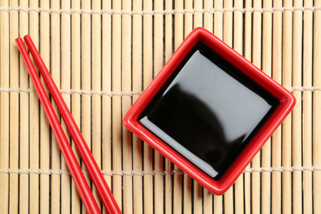 Dish of soy sauce with chopsticks on bamboo mat, flat layの写真素材