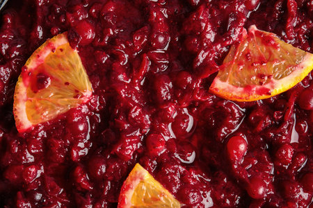 Tasty cranberry sauce with citrus fruit slices as background, top viewの写真素材