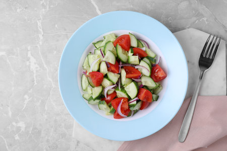 Plate of vegetarian salad with cucumber, tomato and onion served on table, flat layの写真素材