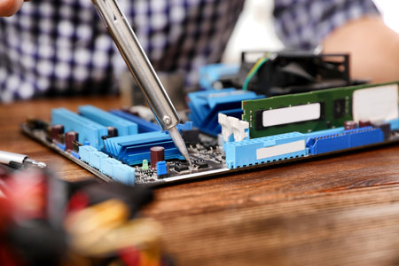 Repairing motherboard with soldering iron on table, closeupの写真素材