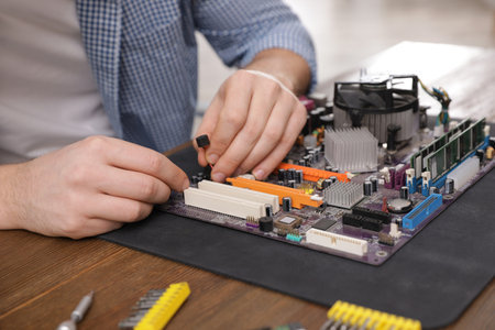 Male technician repairing motherboard at table, closeupの写真素材