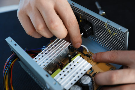 Male technician repairing power supply unit at table, closeupの写真素材