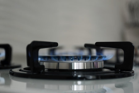 Gas burner with blue flame on modern stove, closeup. Space for textの写真素材