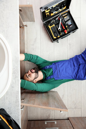 Male plumber repairing kitchen sink, top viewの写真素材