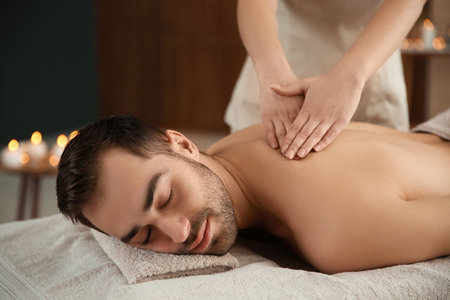 Handsome man receiving back massage in spa salonの写真素材