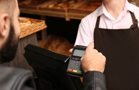 Man with credit card using payment terminal at shop, closeupの写真素材