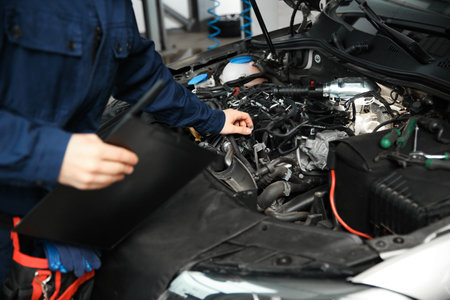 Technician checking modern car at automobile repair shop, closeup