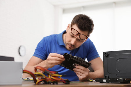 Male technician repairing computer at table indoors