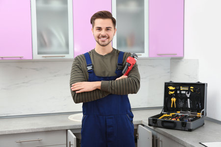 Male plumber with pipe wrench in kitchen. repair serviceの写真素材