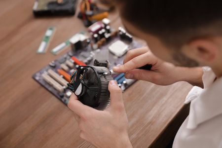 Male technician repairing computer fan at table, closeupの写真素材