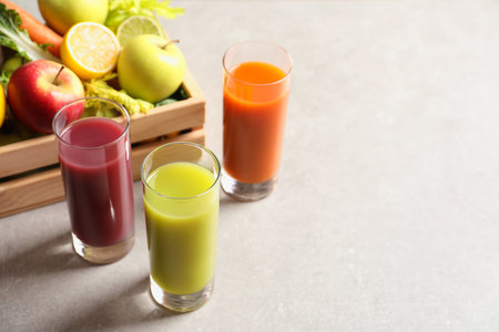 Glasses of different juices and wooden crate with fresh ingredients on table. Space for textの写真素材