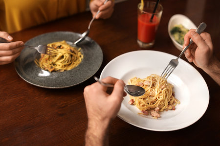Lovely young couple having pasta carbonara for dinner at restaurant, closeup viewの写真素材
