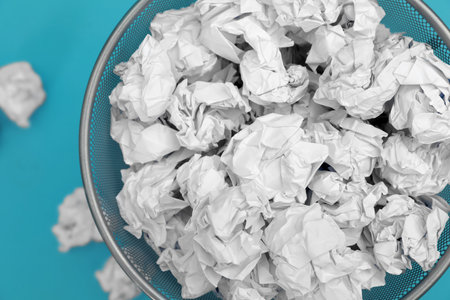 Metal bin with crumpled paper on color background, top viewの写真素材
