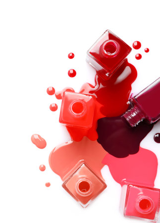 Spilled different nail polishes with bottles on white background, top viewの写真素材
