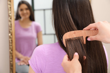 Woman combing friend's hair indoors, closeup viewの写真素材