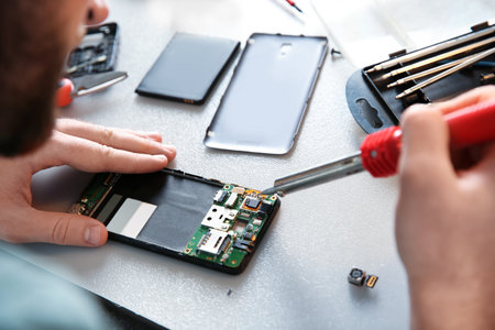 Technician repairing mobile phone at table, closeup