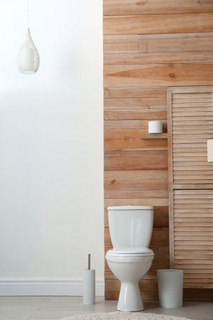 Toilet bowl near wooden wall in modern bathroom interiorの写真素材