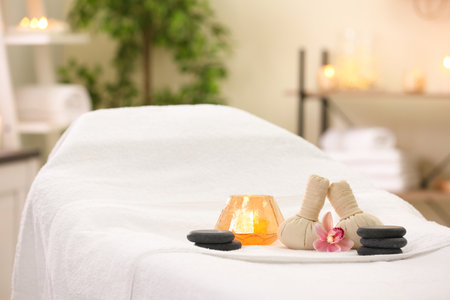 Composition with herbal bags, candle and stones on massage table in spa salonの写真素材