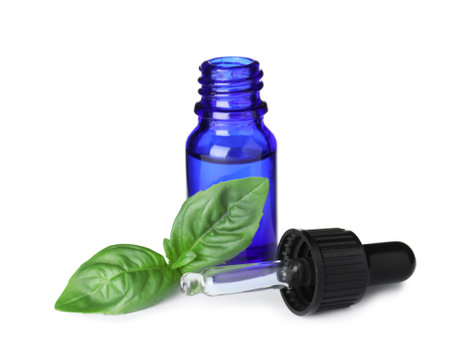 Little bottle of essential oil with dropper and basil on white backgroundの写真素材