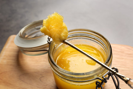 Jar and spoon with clarified butter on wooden board