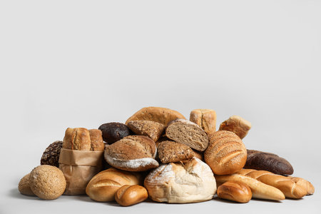 Pile of fresh tasty bread on light backgroundの写真素材