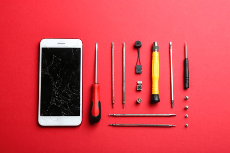 Flat lay composition with broken mobile phone and repair tools on color backgroundの写真素材