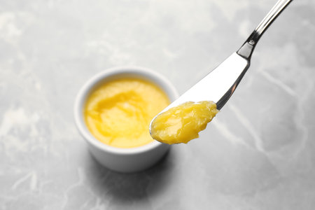 Knife with clarified butter over gray tableの写真素材